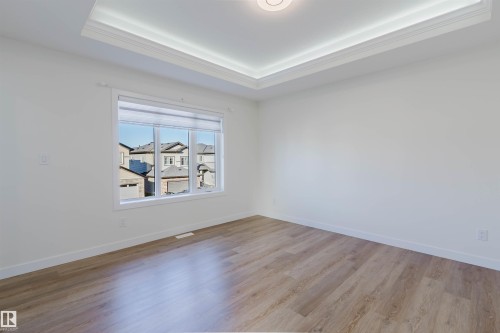 Recessed ceiling with layered crown molding, wood-finish flooring, and white trim - 6047 180 Avenue Nw, Edmonton, AB 
