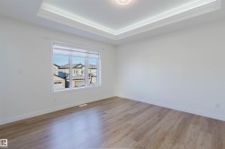 Recessed ceiling with layered crown molding, wood-finish flooring, and white trim - 