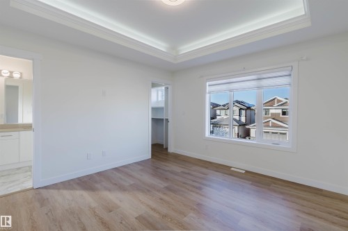 Recessed ceiling with crown molding, wood-finish flooring, white window blinds, built-in shelving, and an en-suite bathroom with a vanity - 6047 180 Avenue Nw, Edmonton, AB 