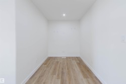 White painted walls, recessed ceiling lighting, wood-finish flooring, and white trim - 