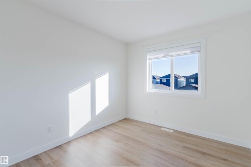 Neutral white walls, wood-finish flooring, and a large window - 6047 180 Avenue Nw, Edmonton, AB 