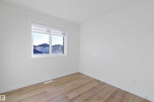 Bright room featuring wood-finish flooring and a window with white trim - 6047 180 Avenue Nw, Edmonton, AB 