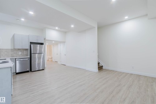 Recessed lighting, wood-finish flooring, stainless steel appliances, light gray cabinetry, and a subway tile backsplash - 6047 180 Avenue Nw, Edmonton, AB 