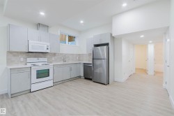 Modern kitchen with light grey cabinetry, white countertops, stainless steel appliances, and wood-finish flooring - 