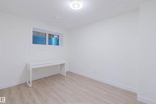 Recessed window with blue-tinted window well, light wood-finish flooring, and white walls - 6047 180 Avenue Nw, Edmonton, AB 
