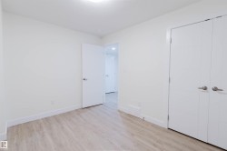 Light wood-finish flooring, white walls, modern ceiling light fixture, white interior door, and double closet doors with horizontal paneling - 