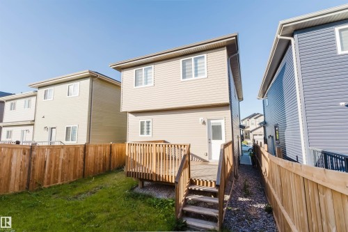 Fenced backyard featuring a wooden deck with stairs, a grass area, and light-colored siding - 6047 180 Avenue Nw, Edmonton, AB 