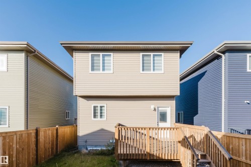 Two-story exterior with horizontal siding, multiple windows, an exterior light fixture, and a built-in wooden deck with stairs - 6047 180 Avenue Nw, Edmonton, AB 