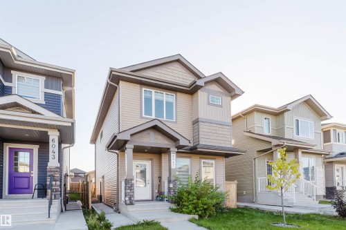 Two-story exterior with light beige siding and stone facade accents - 6047 180 Avenue Nw, Edmonton, AB 
