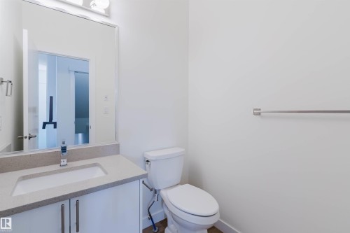 Bathroom featuring a white vanity with an integrated sink, polished chrome faucet, and a large wall-mounted mirror - 6047 180 Avenue Nw, Edmonton, AB 