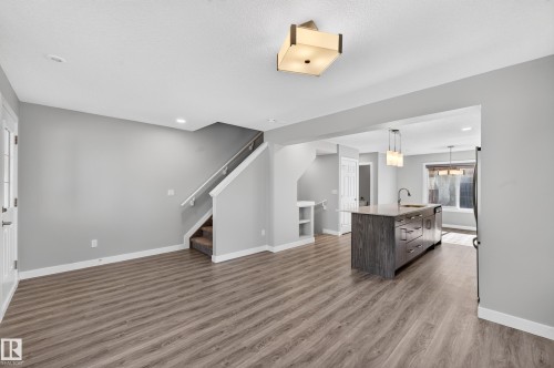 Spacious interior featuring wood-finish flooring, a contemporary kitchen island with an undermount sink, and recessed lighting - #44 3025 151 Av Nw, Edmonton, AB 