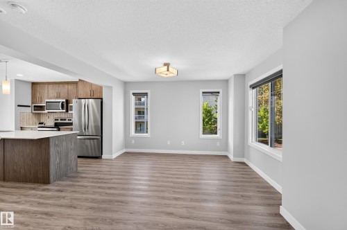 Open-concept layout with wood-finish flooring, recessed lighting, white trim, and a kitchen island with pendant lighting - #44 3025 151 Av Nw, Edmonton, AB 