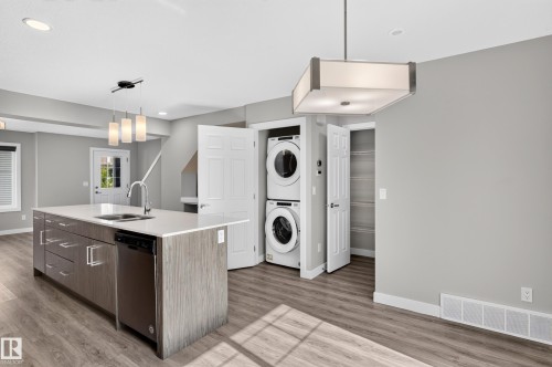 Kitchen island with an undermount sink, stainless steel dishwasher, and a pendant light fixture - #44 3025 151 Av Nw, Edmonton, AB 