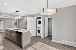Kitchen island with an undermount sink, stainless steel dishwasher, and a pendant light fixture - 