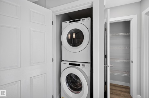 Dedicated laundry closet featuring stacked front-load washers and dryers with modern white finishes and digital controls - #44 3025 151 Av Nw, Edmonton, AB 