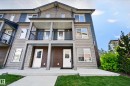 Multi-level townhome exterior featuring an upper balcony with black railings, a ground-level patio, and a combination of horizontal and shingle siding - #44 3025 151 Av Nw, Edmonton, AB 