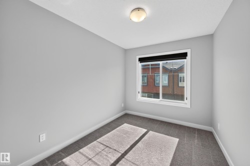 Neutral gray wall finish, white trim, flush mount ceiling light fixture, sliding window, and gray carpeting - #44 3025 151 Av Nw, Edmonton, AB 