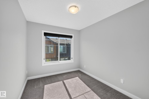 Neutral gray wall paint, white trim, gray carpet flooring, window with black roller shade, and ceiling-mounted light fixture - #44 3025 151 Av Nw, Edmonton, AB 