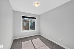Neutral gray wall paint, white trim, gray carpet flooring, window with black roller shade, and ceiling-mounted light fixture - 