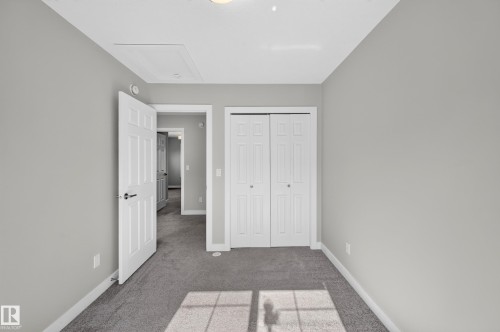 Neutral gray wall paint, gray carpet flooring, white trim, white paneled doors, and a ceiling-mounted light fixture - #44 3025 151 Av Nw, Edmonton, AB 