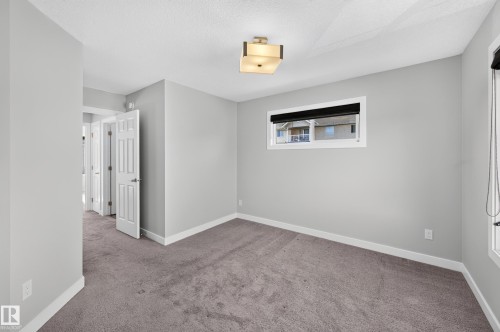 Recessed window with black privacy shade, overhead semi-flush mount light fixture, textured ceiling, light gray wall paint, and gray carpeting - #44 3025 151 Av Nw, Edmonton, AB 