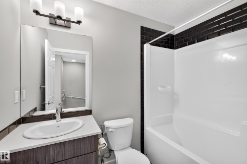 Modern bathroom featuring a wood-finish vanity with a round vessel sink, quartz countertop, and chrome faucet - #44 3025 151 Av Nw, Edmonton, AB 