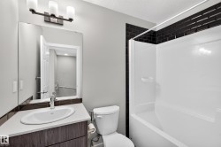 Modern bathroom featuring a wood-finish vanity with a round vessel sink, quartz countertop, and chrome faucet - 