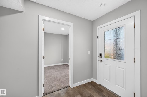 Modern entry door with privacy glass panel and dark wood-finish flooring - #44 3025 151 Av Nw, Edmonton, AB 