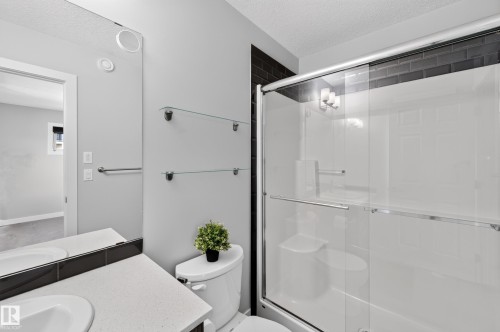Walk-in shower with black subway tile surround, clear glass enclosure, and built-in seating - #44 3025 151 Av Nw, Edmonton, AB 