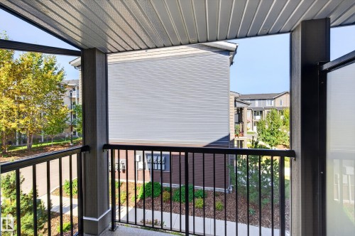 Balcony with black metal railings, a corrugated ceiling, and exterior roller shades - #44 3025 151 Av Nw, Edmonton, AB 