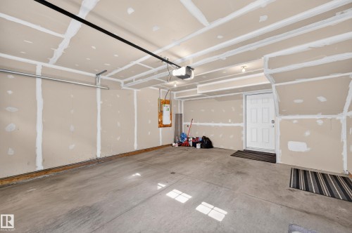 Attached garage with concrete flooring, overhead lighting, and an overhead garage door track system - #44 3025 151 Av Nw, Edmonton, AB 