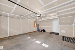 Attached garage with concrete flooring, overhead lighting, and an overhead garage door track system - 