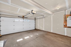Concrete flooring, exposed ceiling beams, overhead lighting, and an automatic garage door opener - 