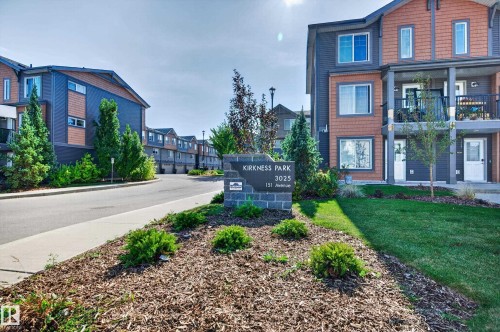 Multi-level townhome featuring a balcony, integrated garage, and a combination of blue and orange siding - #44 3025 151 Av Nw, Edmonton, AB 
