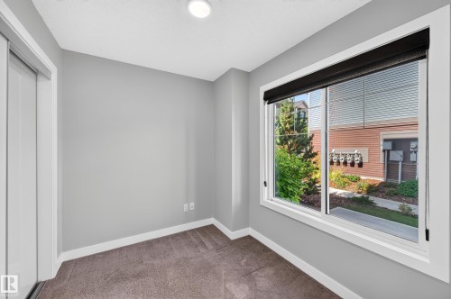 Recessed ceiling lighting, a large window with roller shades, neutral carpeting, and a sliding closet door - #44 3025 151 Av Nw, Edmonton, AB 