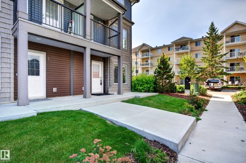 Ground-level entryways with white doors, front lawn area, and surrounding landscaping - #44 3025 151 Av Nw, Edmonton, AB 