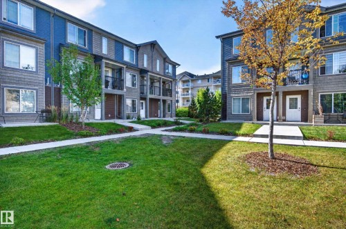 Contemporary multi-story townhomes featuring balconies, ground-level patios, and a central landscaped courtyard with established trees and concrete pathways - #44 3025 151 Av Nw, Edmonton, AB 