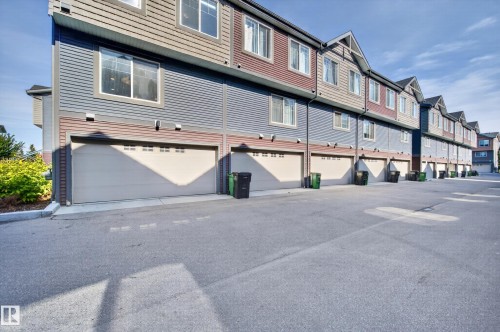 Multi-level townhome featuring horizontal siding, multiple windows, and an attached garage with an overhead door - #44 3025 151 Av Nw, Edmonton, AB 