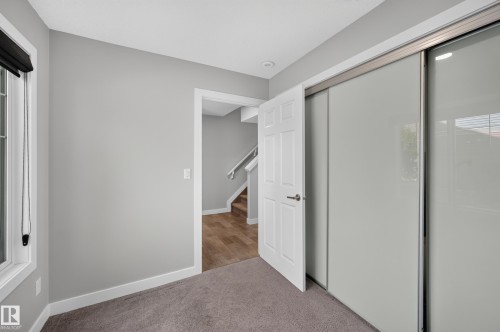 Window with black roller blind, solid core door, sliding closet doors, and light gray wall paint - #44 3025 151 Av Nw, Edmonton, AB 