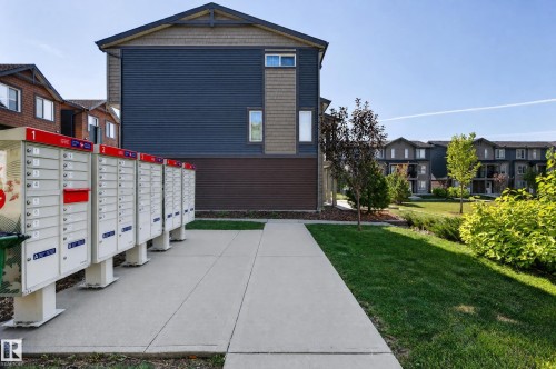 Community mailboxes with a concrete pathway and landscaped green space - #44 3025 151 Av Nw, Edmonton, AB 