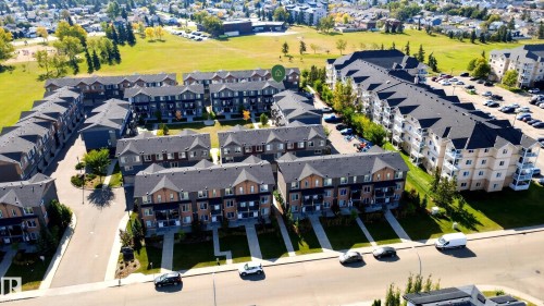 Townhome community featuring multi-story units with dark pitched roofs, light-colored exteriors, and individual balconies - #44 3025 151 Av Nw, Edmonton, AB 