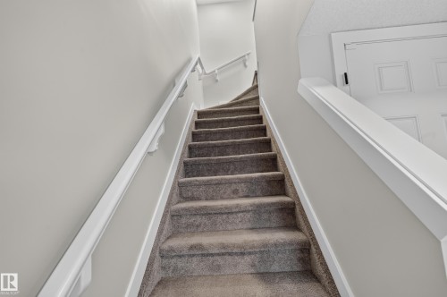 Carpeted staircase with white handrails and painted walls - #44 3025 151 Av Nw, Edmonton, AB 