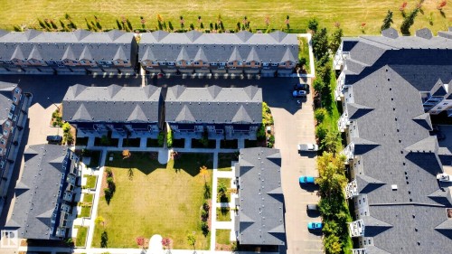 Townhome community with multiple residential buildings, paved parking areas, and a central green space - #44 3025 151 Av Nw, Edmonton, AB 