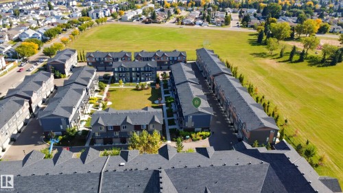 Townhome community featuring multiple buildings, manicured green spaces, and surrounding residential areas - #44 3025 151 Av Nw, Edmonton, AB 