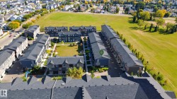 Townhome community featuring multiple buildings, manicured green spaces, and surrounding residential areas - 