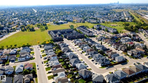 Aerial perspective showcasing a residential neighborhood with detached homes, townhouses, and open green spaces - #44 3025 151 Av Nw, Edmonton, AB 