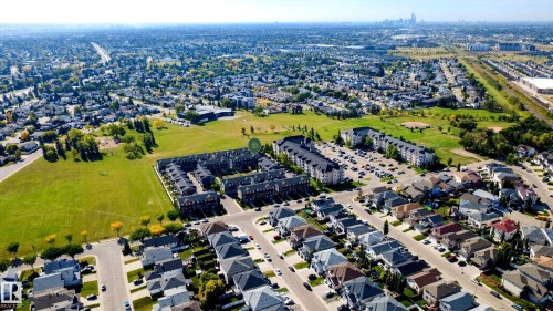 Aerial perspective showcasing a residential neighborhood with detached homes, multi-unit buildings, and expansive green spaces - #44 3025 151 Av Nw, Edmonton, AB 