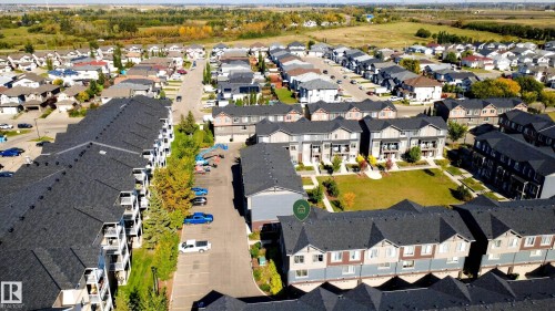 Residential development featuring apartment buildings and townhomes, surrounded by green spaces and adjacent to undeveloped land - #44 3025 151 Av Nw, Edmonton, AB 