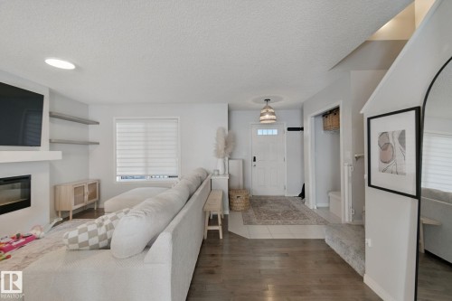 Wood-finish flooring, recessed lighting, and built-in fireplace with floating shelving - 8535 Ellis Link Link Nw, Edmonton, AB 