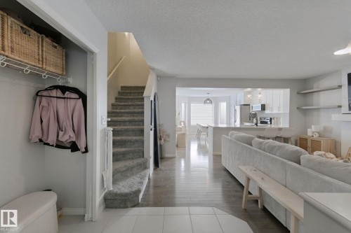 Open-concept living space featuring wood-finish flooring, a carpeted staircase, and a kitchen with a peninsula island - 8535 Ellis Link Link Nw, Edmonton, AB 